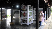 Pengunjung menyaksikan foto karya Pewarta Foto Indonesia (PFI) Aceh yang dipamerkan di Rumah Adat Aceh, Banda Aceh, Minggu (25/12/2022).