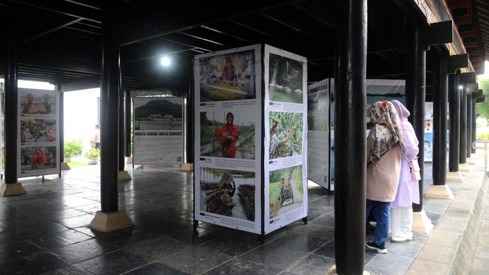Pengunjung menyaksikan foto karya Pewarta Foto Indonesia (PFI) Aceh yang dipamerkan di Rumah Adat Aceh, Banda Aceh, Minggu (25/12/2022). Pameran foto itu bertema 