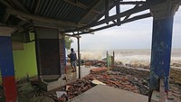 Warga melihat bangunan rumah makan yang rusak akibat diterjang ombak dan banjir rob di Desa Eretan Kulon, Kandanghaur, Indramayu, Jawa Barat, Senin (26/12/2022).  