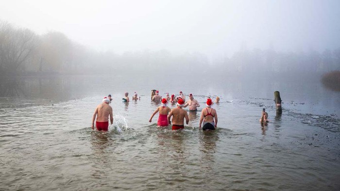 Members of the Berliner Seehunde (Berlin seals) swimming club take their traditional Christmas bath at the Oranke lake on December 25, 2022 in Berlin. (Photo by Tobias Schwarz / AFP) (Photo by TOBIAS SCHWARZ/AFP via Getty Images)