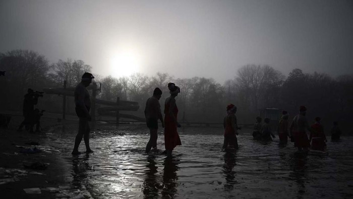 Pertahankan Tradisi Natal, Orang-orang Ini Berenang di Danau yang Membeku Members of the Berliner Seehunde (Berlin seals) swimming club take their traditional Christmas bath at the Oranke lake on December 25, 2022 in Berlin. (Photo by Tobias Schwarz / AFP) (Photo by TOBIAS SCHWARZ/AFP via Getty Images)