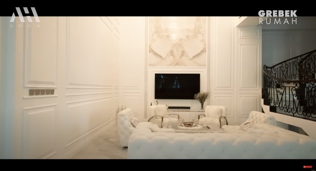 Di samping dapur dan ruang makannya terdapat ruang keluarga yang juga didominasi oleh warna putih. Ruang keluarga tersebut tampak nyaman dengan dilengkapi sofa putih dan sebuah televisi. Foto: YouTube/AH