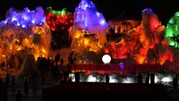 Suasana air terjun beku pada malam hari yang terlihat berwarna-warni.