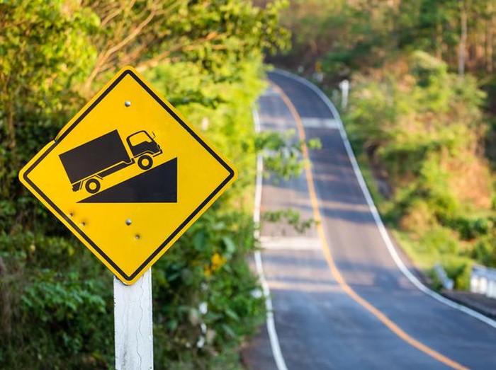 Steep grade traffic sign on the roadside, uphill asphalt road in countryside