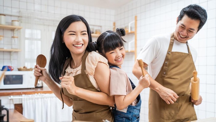 Asian happy family stay home in kitchen bake bakery and dance together. Fatherand mother spend free time with young little girl daughter make food, Kid enjoy parenting activity relationship in house.