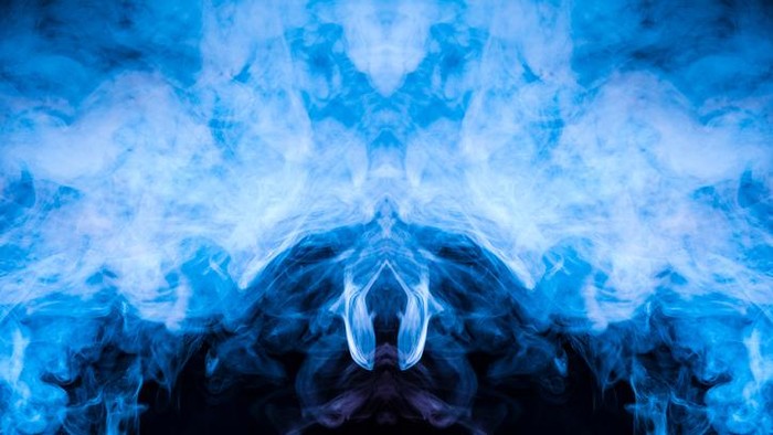 A multi-colored pattern of blue smoke of a mystical shape in the form of a face and a ghosts head or a strange creature on a black isolated background. Abstract pattern in of waves and steam