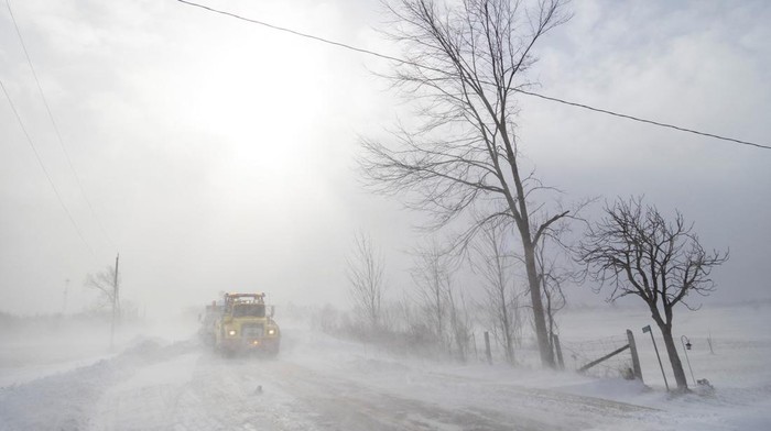 Larry Miskolczi and Chris Ricker help snow plow driver Gord Bartlett with a tow during a winter storm in Canfield Ontario, Canada.  REUTERS/Carlos Osorio