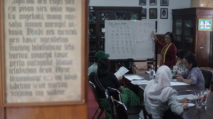 Abdi keraton menjelaskan kepada peserta tulisan aksara jawa saat mengikuti workshop Menulis dan Membaca Aksara Jawa di Perpustakaan Reksa Pustaka, Pura Mangkunegaran, Solo, Jawa Tengah, Selasa (27/12/2022). Kegiatan tersebut untuk mengenalkan kembali tulisan aksara jawa sekaligus upaya untuk melestarikan kebudayaan jawa. ANTARA FOTO/Mohammad Ayudha/aww.