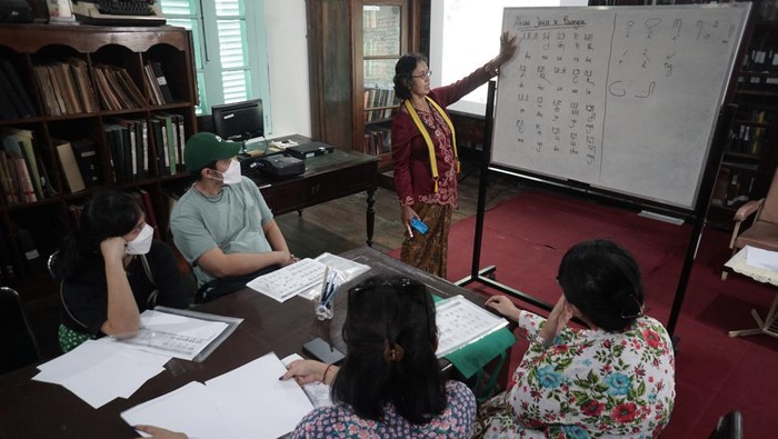 Abdi keraton menjelaskan kepada peserta tulisan aksara jawa saat mengikuti workshop Menulis dan Membaca Aksara Jawa di Perpustakaan Reksa Pustaka, Pura Mangkunegaran, Solo, Jawa Tengah, Selasa (27/12/2022). Kegiatan tersebut untuk mengenalkan kembali tulisan aksara jawa sekaligus upaya untuk melestarikan kebudayaan jawa. ANTARA FOTO/Mohammad Ayudha/aww.