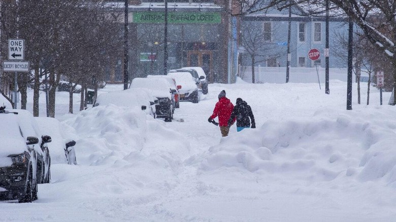 Penampakan Badai Salju Mematikan di AS People move about the streets of the Elmwood Village neighborhood of Buffalo, N.Y. Monday, Dec. 26, 2022, after a massive snow storm blanketed the city. Along with drifts and travel bans, many streets were impassible due to abandoned vehicles. (AP Photo/Craig Ruttle)