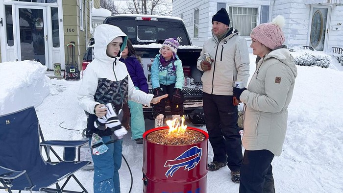 A group of neighbors gather around a fire pit on Culver Road after clearing snow in Buffalo, N.Y., Monday, Dec. 26, 2022. The region is digging out from a pre-Christmas blizzard that delivered hurricane-force winds and more than 4 feet of snow. (AP Photo/Carolyn Thompson)