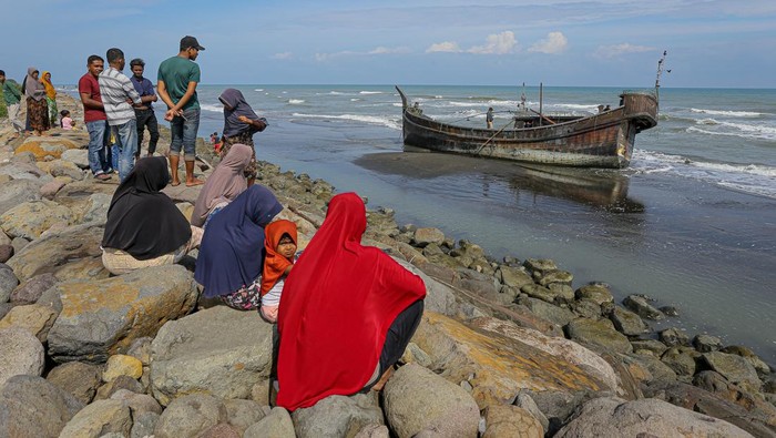 Villagers look at a wooden boat used by Rohingya people in Pidie, Aceh province on December 27, 2022. - Rohingya refugees received emergency medical treatment after a boat carrying nearly 200 people came ashore in Indonesia on December 26, authorities said, in the fourth such landing in the country in recent months. (Photo by AMANDA JUFRIAN / AFP) (Photo by AMANDA JUFRIAN/AFP via Getty Images)