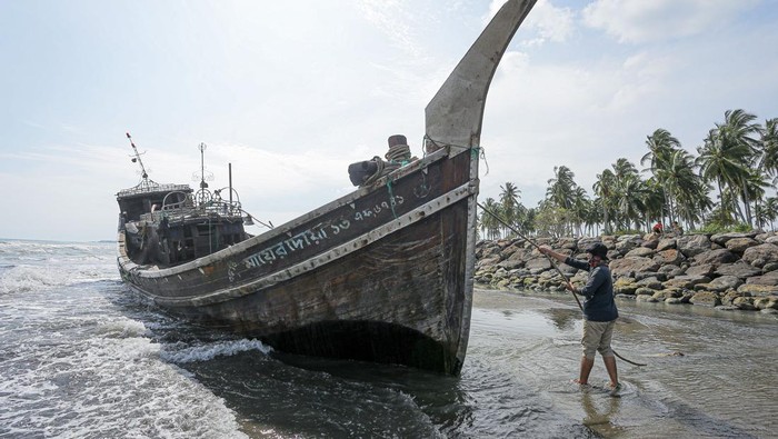 Villagers look at a wooden boat used by Rohingya people in Pidie, Aceh province on December 27, 2022. - Rohingya refugees received emergency medical treatment after a boat carrying nearly 200 people came ashore in Indonesia on December 26, authorities said, in the fourth such landing in the country in recent months. (Photo by AMANDA JUFRIAN / AFP) (Photo by AMANDA JUFRIAN/AFP via Getty Images)