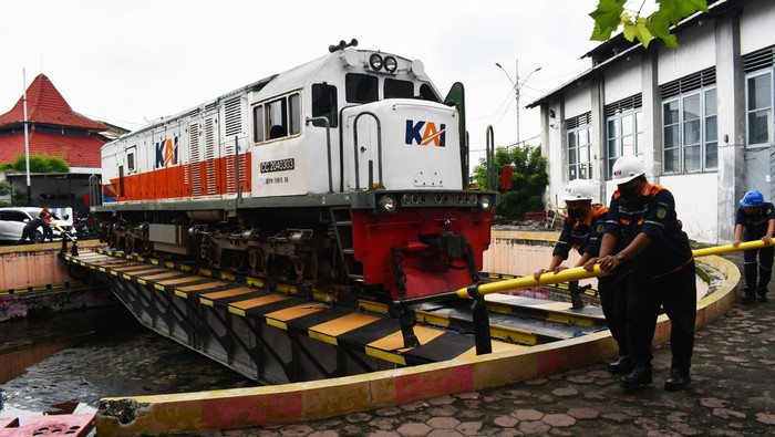 Sejumlah petugas memutar lokomotif Kereta Api (KA) seberat sekitar 80 ton dengan cara mendorong di atas sepur putar sampai mencapai posisi 180 derajat di Dipo Stasiun KA Madiun, Jawa Timur, Senin (26/12/2022). Setiap harinya dua lokomotif KA dari Jakarta atau Bandung harus diputar di sepur putar tersebut sebelum berbalik arah menuju Stasiun KA asal. ANTARA FOTO/Siswowidodo/wsj.