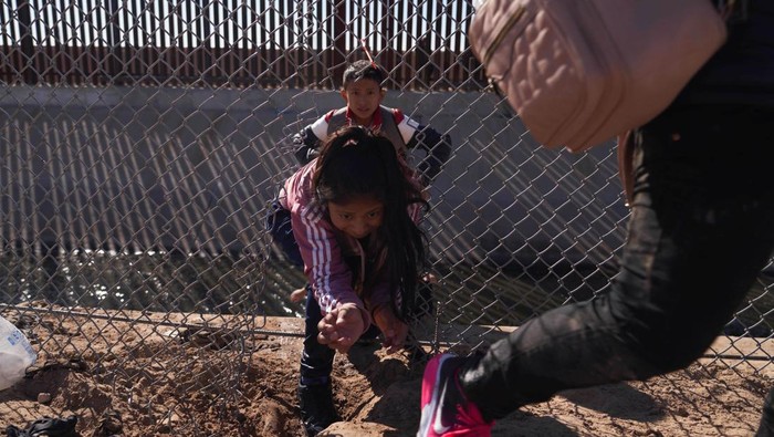 Perjuangan Migran Merayap di Perbatasan Demi Sampai AS Migrants illegally cross into the United States from Mexico via a hole cut in the border fence in El Paso, Texas, US on December 21, 2022. - The southern border of the United States has been officially closed to immigrants without visas for more than two years under a controversial health measure invoked by then-president Donald Trump during the Covid-19 pandemic. Title 42 prevents asylum seekers from presenting themselves at ports of entry, allowing border patrol officers to turn them away without starting an asylum application. (Photo by Allison Dinner / AFP) (Photo by ALLISON DINNER/AFP via Getty Images)