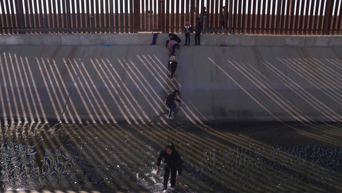 Migrants illegally cross into the United States from Mexico via a hole cut in the border fence in El Paso, Texas, US on December 21, 2022. - The southern border of the United States has been officially closed to immigrants without visas for more than two years under a controversial health measure invoked by then-president Donald Trump during the Covid-19 pandemic. Title 42 prevents asylum seekers from presenting themselves at ports of entry, allowing border patrol officers to turn them away without starting an asylum application. (Photo by Allison Dinner / AFP) (Photo by ALLISON DINNER/AFP via Getty Images)
