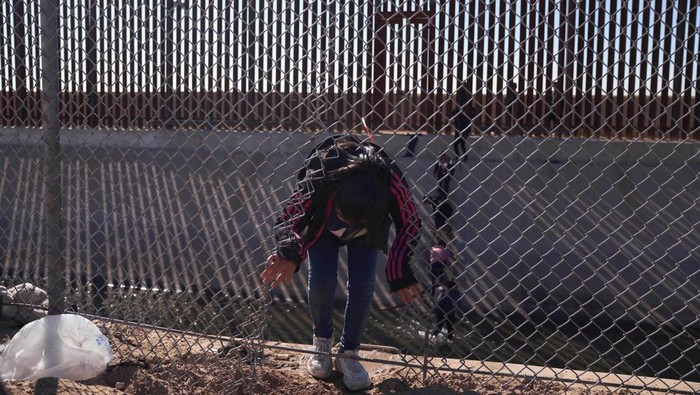 Perjuangan Migran Merayap di Perbatasan Demi Sampai AS Migrants illegally cross into the United States from Mexico via a hole cut in the border fence in El Paso, Texas, US on December 21, 2022. - The southern border of the United States has been officially closed to immigrants without visas for more than two years under a controversial health measure invoked by then-president Donald Trump during the Covid-19 pandemic. Title 42 prevents asylum seekers from presenting themselves at ports of entry, allowing border patrol officers to turn them away without starting an asylum application. (Photo by Allison Dinner / AFP) (Photo by ALLISON DINNER/AFP via Getty Images)