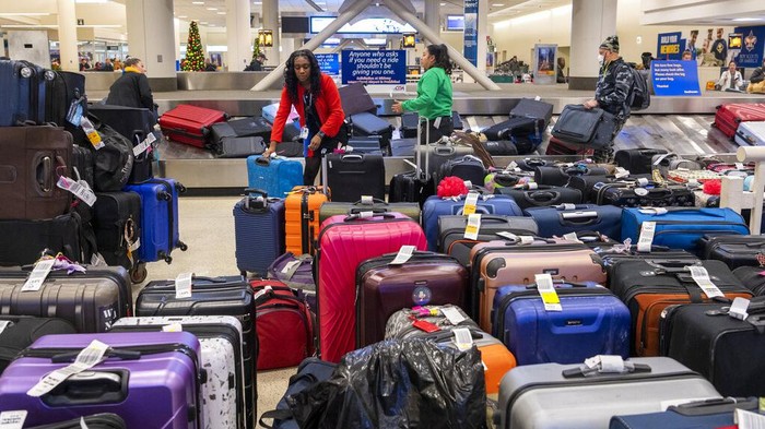 Ribuan Pelancong Terjebak di Bandara AS Gegara Badai Salju A Southwest Airlines employee helps manage luggage at Chicago Midway International Airport, Monday, Dec. 26, 2022, in Chicago. (Tyler Pasciak LaRiviere/Chicago Sun-Times via AP)