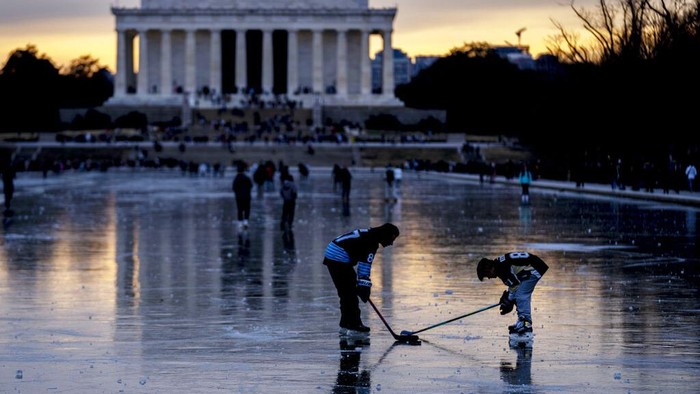 Orang-orang bermain hoki es di atas kolam beku di dekat Lincoln Memorial, Washington D.C., Amerika Serikat, Senin (26/12/2022).