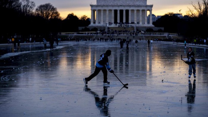 Orang-orang bermain hoki es di atas kolam beku di dekat Lincoln Memorial, Washington D.C., Amerika Serikat, Senin (26/12/2022).