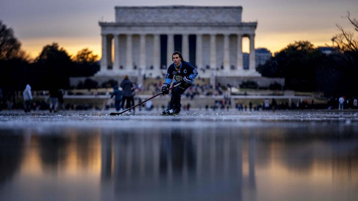 Warga AS Main Hoki Es di Kolam yang Membeku Orang-orang bermain hoki es di atas kolam beku di dekat Lincoln Memorial, Washington D.C., Amerika Serikat, Senin (26/12/2022).