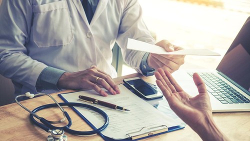 Doctor or physician writing diagnosis and giving a medical prescription to female Patient