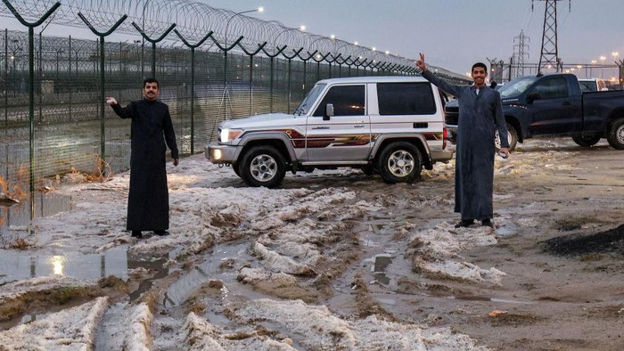 People inspect hail particles lying on the side of a road after a storm in the Umm al-Haiman district, about 55 kilometres south of Kuwait City, on December 27, 2022. (Photo by YASSER AL-ZAYYAT / AFP) (Photo by YASSER AL-ZAYYAT/AFP via Getty Images)