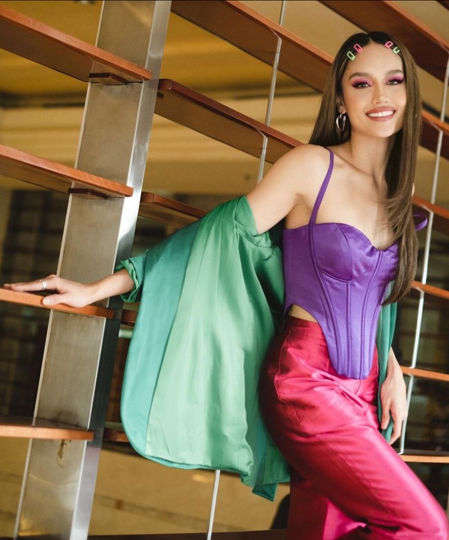 Cinta Laura tak ragu bermain tabrak warna dengan memadukan palet cerah dalam satu busana. Misalnya saja atasan ungu dengan celana fuchsia dan blazer hijau. Foto: Instagram/@claurakiehl