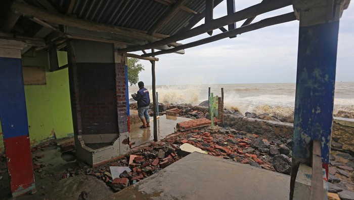 Warga melihat bangunan rumah makan yang rusak akibat diterjang ombak dan banjir rob di Desa Eretan Kulon, Kandanghaur, Indramayu, Jawa Barat, Senin (26/12/2022). Banjir rob yang disertai gelombang tinggi menyebabkan beberapa bangunan di sekitar pantai tersebut mengalami kerusakan. ANTARA FOTO/Dedhez Anggara/tom.