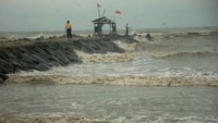 Warga berdiri di konstruksi pemecah ombak di pinggir Pantai  Utara, Desa Larangan, Kabupaten Tegal, Jawa Tengah, Selasa (27/12/2022). Badan Meteorologi Klimatologi dan Geofisika (BMKG) Tegal memperkirakan tinggi gelombang di Laut Jawa berkisar 2,5 - 4 meter dan mengingatkan warga di pinggir pantai dan kapal-kapal kecil agar waspada akan adanya ombak besar yang terjadi sewaktu-waktu. ANTARA FOTO/Oky Lukmansyah  