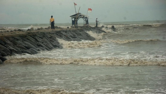Cuaca Ekstrem Porakporanda Daerah Perairan Indonesia Warga berdiri di konstruksi pemecah ombak di pinggir Pantai Utara, Desa Larangan, Kabupaten Tegal, Jawa Tengah, Selasa (27/12/2022). Badan Meteorologi Klimatologi dan Geofisika (BMKG) Tegal memperkirakan tinggi gelombang di Laut Jawa berkisar 2,5 - 4 meter dan mengingatkan warga di pinggir pantai dan kapal-kapal kecil agar waspada akan adanya ombak besar yang terjadi sewaktu-waktu. ANTARA FOTO/Oky Lukmansyah/aww.
