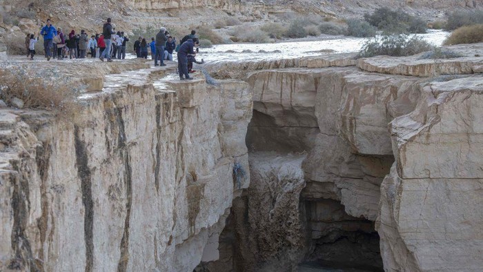 Gurun Negev Israel Dilanda Banjir Bandang, Jadi Tontonan Warga Israelis watch as a flash-flood takes place in the Negev desert East of the Israeli city of Dimona on December 26, 2022, following heavy rainfall over the region. (Photo by MENAHEM KAHANA / AFP) (Photo by MENAHEM KAHANA/AFP via Getty Images)