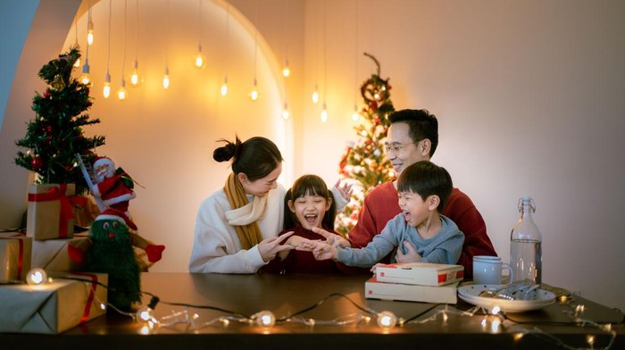 Asian family sitting at dinner table having a Christmas eve dinner together.