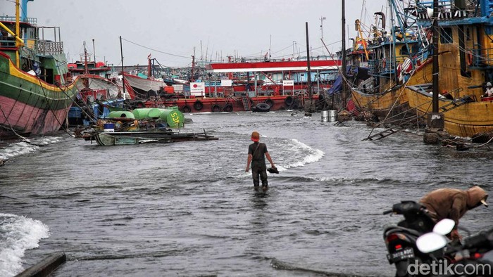 Nelayan Melintasi banjir rob saat cuaca buruk di Pelabuhan Muara Baru, Penjaringan, Jakarta Utara, Rabu (28/12/2022).