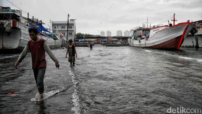 Nelayan Melintasi banjir rob saat cuaca buruk di Pelabuhan Muara Baru, Penjaringan, Jakarta Utara, Rabu (28/12/2022).