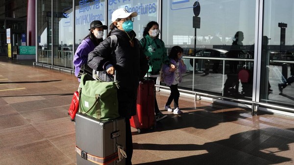 Penumpang yang memakai masker tiba di terminal bandara Ibukota di Beijing. Keputusan China untuk mengakhiri karantina bagi pelancong dari luar negeri sebagai langkah penting untuk menghidupkan kembali aktivitas bisnis yang merosot disambut baik. AP/Ng Han Guan