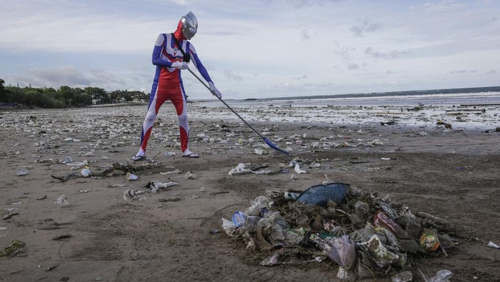 BALI, INDONESIA - DECEMBER 29: A Japanese tourist cosplayed as Ultraman character cleans up trashes that washed ashore in Kuta Beach, Bali, Indonesia on December 29, 2022. During monsoon Balis popular Kuta Beach is affected by tons of marine pollution. Trashes of plastic rubbish, woods and other discarded materials washed ashore along the coastline. Coast guards, tourists and locals side by side cleaning the beach as thousands of tourists visit the island during the holiday season of New Year. (Photo by Johannes P. Christo/Anadolu Agency via Getty Images)