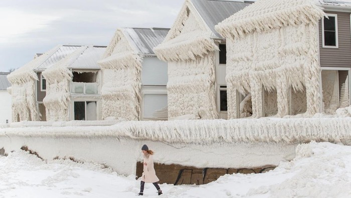 Dahsyat! Rumah-rumah di Tepi Pantai Kanada Diselimuti Es People walk by homes covered in ice at the waterfront community of Crystal Beach in Fort Erie, Ontario, Canada, on December 28, 2022, following a massive snow storm that knocked out power in the area to thousands of residents. (Photo by Cole Burston / AFP) (Photo by COLE BURSTON/AFP via Getty Images)