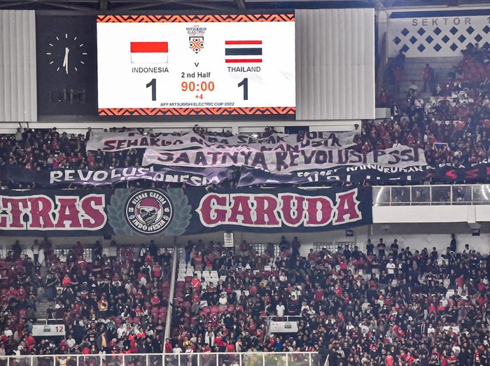 Seorang suporter Timnas Indonesia membentangkan poster saat pertandingan sepak bola Grup A Piala AFF 2022 melawan Thailand di Stadion Utama Gelora Bung Karno (SUGBK), Jakarta, Kamis (29/12/2022). Aksi tersebut terkait tuntutan agar pemerintah mengusut tuntas tragedi Kanjuruhan yang menelan korban 135 orang meninggal dan ratusan lainnya luka-luka.