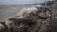 Seorang anak berdiri melihat penahan gelombang yang rusak.