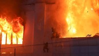 Gambar dari lokasi menunjukkan petugas pemadam kebakaran berjuang memadamkan api yang melalap bangunan. Petugas penyelamat terlihat berusaha menyelamatkan kerumunan orang di balkon. STR/AFP/Getty Images  