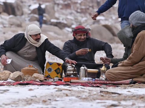 Warga Saudi mencairkan salju untuk membuat kopi di Jabal al-Lawz (Gunung Almond), sebelah barat kota Tabuk di Saudi pada 17 Januari 2022. (IBRAHIM ASSIRI/AFP via Getty Images)