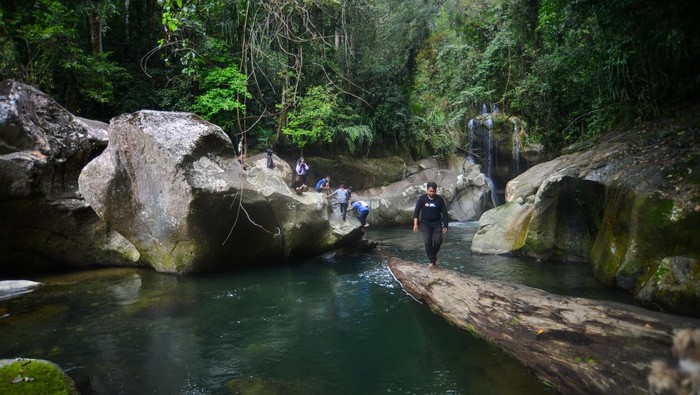 Pengunjung berenang di kolam Lubuk Nyarai, hutan Gamaran, Lubuk Alung, Kabupaten Padang Pariaman, Sumatera Barat, Rabu (28/12/2022). Wisata petualangan Lubuk Nyarai yang dapat ditempuh dengan treking sejauh 5,5 kilometer tersebut menyajikan air terjun dan kolam alami yang terbentuk oleh fenomena breksi atau pusaran air yang menggerus dinding kolam selama ribuan tahin, sehingga membuat kolam terus membesar. ANTARA FOTO/Iggoy el Fitra/foc.