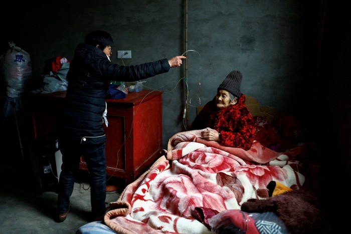 Liao Xiaofeng, 47, prepares an oxygen concentrator for her mother Chen Lifen, 86, as they arrive home from a clinic in a village of Lezhi county after strict measures to curb the coronavirus disease (COVID-19) were removed nationwide, in Ziyang, Sichuan province, China December 29, 2022. REUTERS/Tingshu Wang