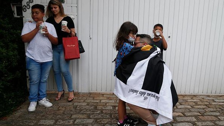 Duka Mendalam Para Suporter Atas Wafatnya Sang Legenda Pele A fan of Brazilian football legend Pele wrapped in a flag of Brazilian team Santos, embraces a girl in front of the Albert Einstein Israelite Hospital, where Pele died after a long battle with cancer, in Sao Paulo, Brazil, on December 29, 2022. - Brazilian football icon Pele, widely regarded as the greatest player of all time and a three-time World Cup winner who masterminded the