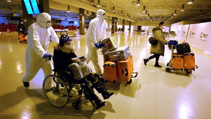 TOPSHOT - Workers wearing protective masks and suits help Chinese travellers leaving the arrival hall of RomeFiumicino International Airport, near Rome, on December 29, 2022 after being tested for the Covid-19 coronavirus. (Photo by Filippo MONTEFORTE / AFP) (Photo by FILIPPO MONTEFORTE/AFP via Getty Images)