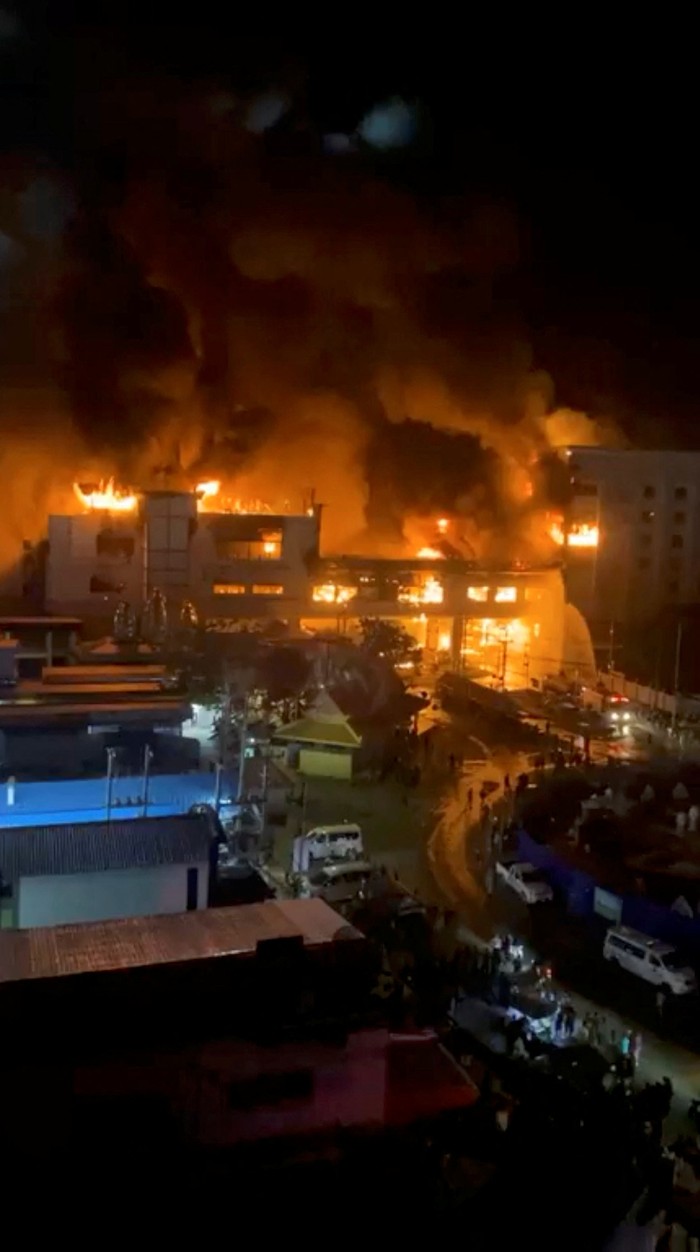 Cambodian police officers ride a motorcycle past the Grand Diamond City hotel-casino, as Thai and Cambodian rescuers struggle to extricate dozens of people feared trapped after a fire broke, killing at least 10 and injuring dozens in Poipet near Thailand border, Cambodia, December 29, 2022. REUTERS/Athit Perawongmetha     TPX IMAGES OF THE DAY