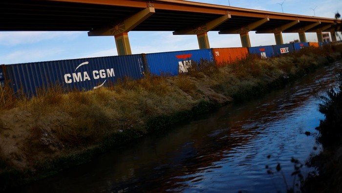Kontainer Hadang Migran Masuk AS Asylum-seeking migrants walk past a fence near containers that were placed in El Paso, Texas, on the banks of the Rio Bravo river, the border between the U.S. and Mexico, with the purpose of reinforcing border security and inhibiting the crossing of migrants into the U.S., seen from Ciudad Juarez, Mexico, December 29, 2022. REUTERS/Jose Luis Gonzalez