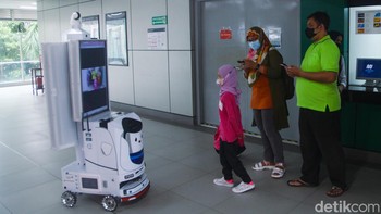 Robot DINA berbentuk seperti koper putih beroda empat dengan layar besar dan kamera yang terintegrasi.  