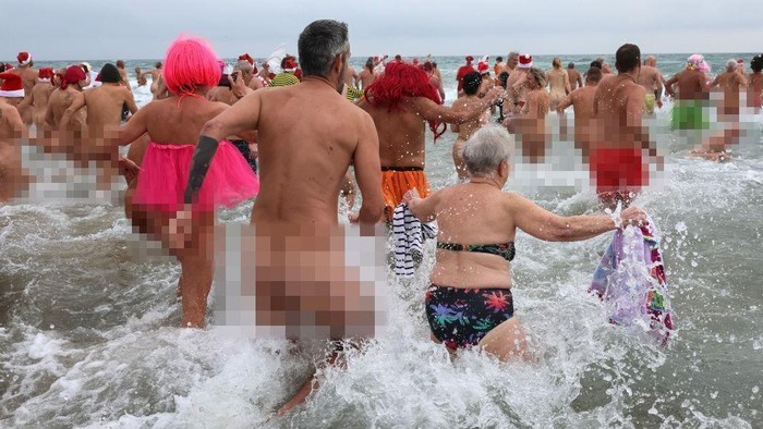 1245897881 EDITORS NOTE: Graphic content / People take part in a traditional sea bath to mark the New Year's celebrations on a nudist beach in Le Cap d'Agde, southern France, on December 31, 2022. (Photo by Pascal GUYOT / AFP) (Photo by PASCAL GUYOT/AFP via Getty Images)